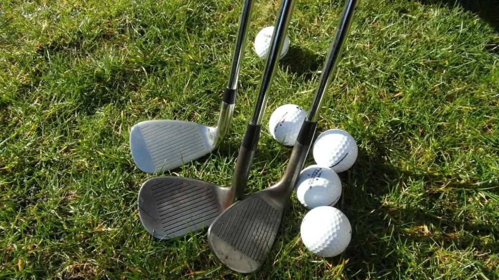 Golf clubs with golf balls on green