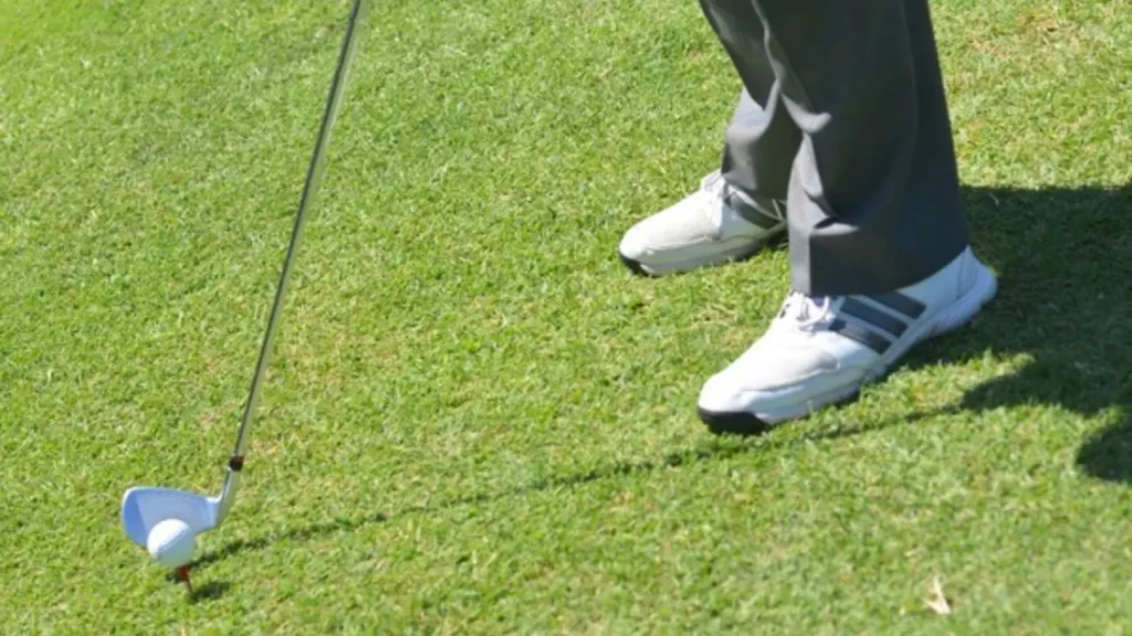 Golfer hitting golf ball on green