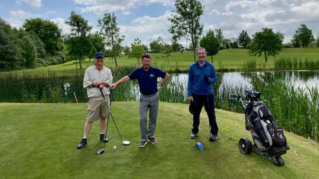 A group of golfers standing on a golf course in front of a lake