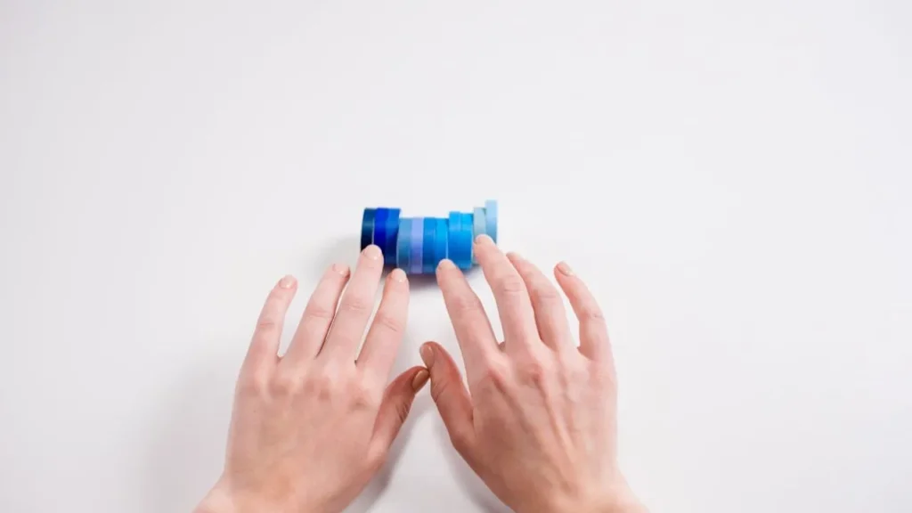 A person holding different color finger tapes on a white background