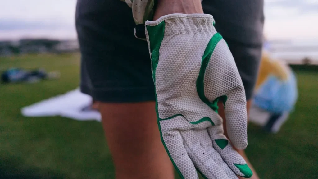 A golfer wearing a white and green golf glove