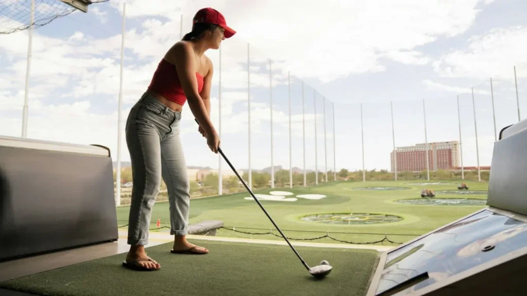 A female golfer about to hit a golf ball at a driving range