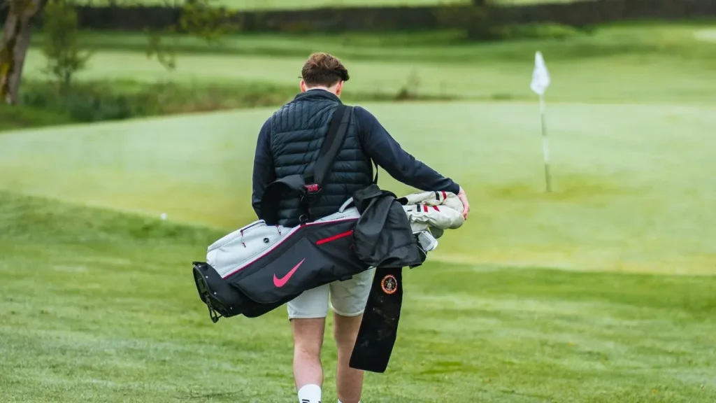 Golfer carrying a Nike golf bag on a golf course