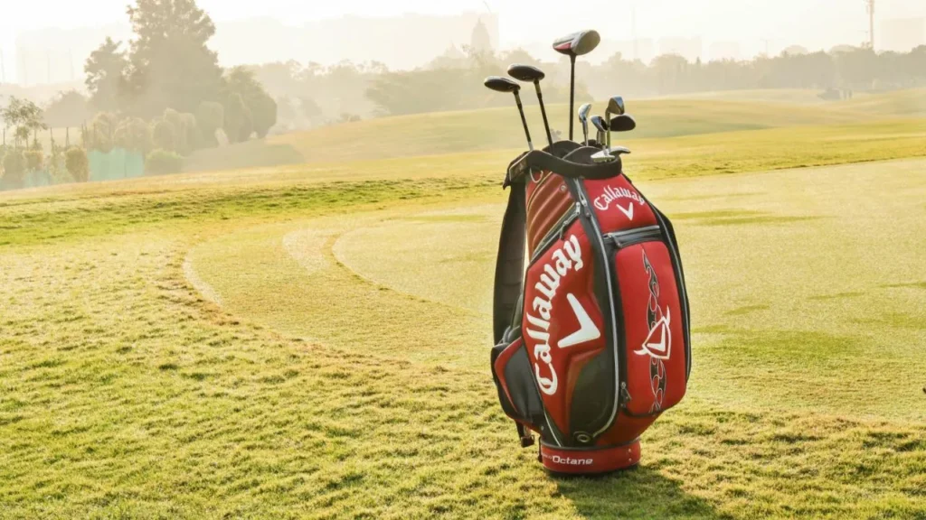 Red Callaway golf bag sitting on a green golf course